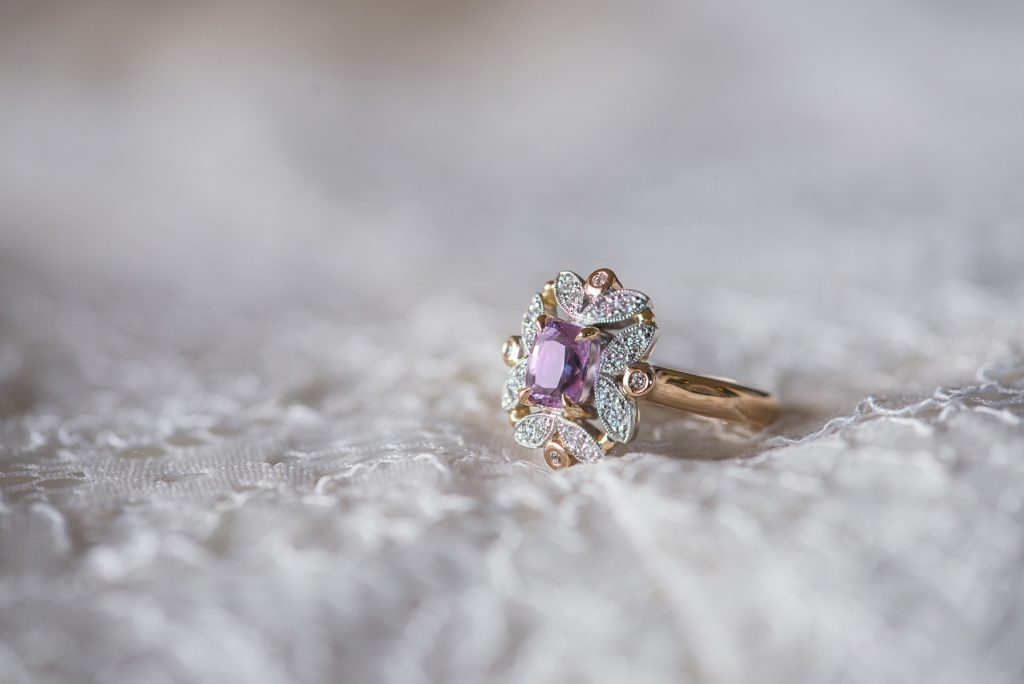 Engagement ring with purple stone lying on wedding dress fabric