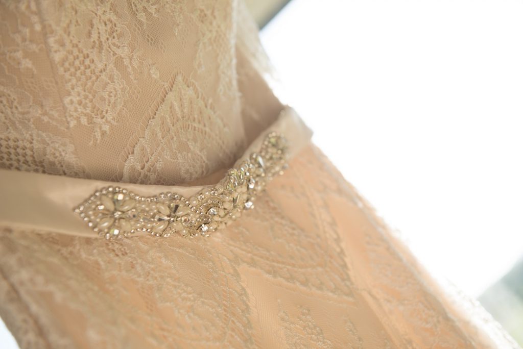 Close up mid section of a wedding dress wth lace overlap featuring a beaded belt