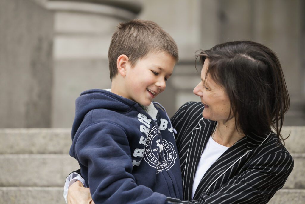 Woman holding a young male child in her arms, smiling at each other